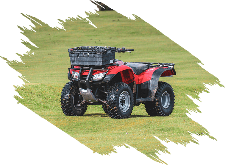 A red and black four wheeler parked in the grass.