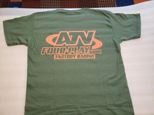 A green t-shirt with an orange and black logo.