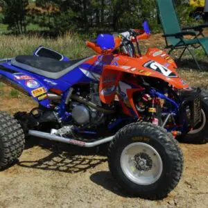 A red and blue atv parked on top of a dirt field.
