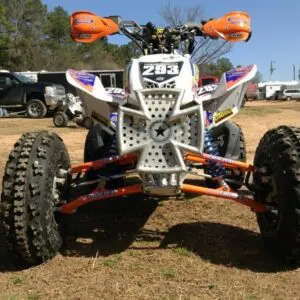 A white and orange atv parked in the dirt.