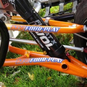 A close up of the front forks on an orange bicycle.
