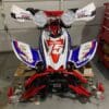 A red, white and blue motorcycle is parked in the garage.