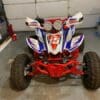 A red, white and blue atv parked in the garage.