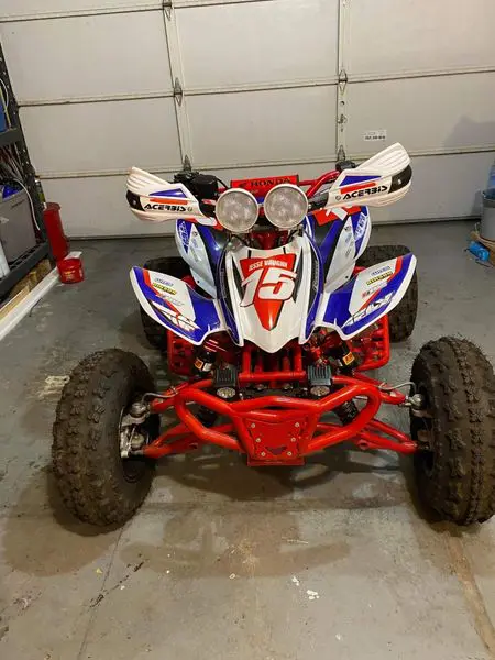 A red, white and blue atv parked in the garage.