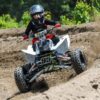 A person on a four wheeler riding through the mud.