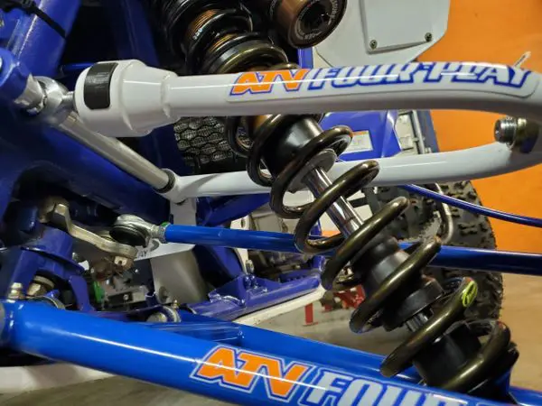 A close up of the front forks and suspension on a blue bicycle.