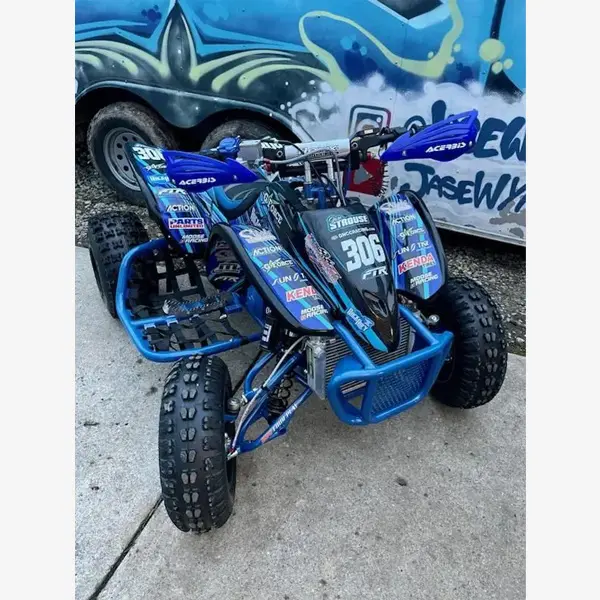 A blue and black four wheeler parked on the side of road.