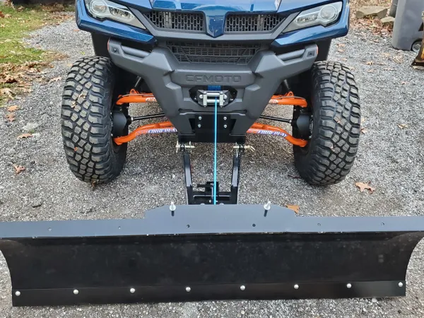 A close up of the front end of an atv with a plow attached.
